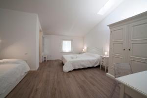 维罗纳Agriturismo Corte Rondinella的一间白色卧室,配有两张床和窗户