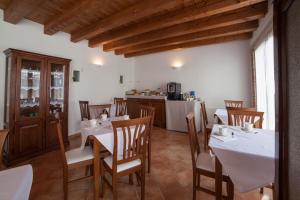 维罗纳Agriturismo Corte Rondinella的用餐室配有白色的桌子和木椅