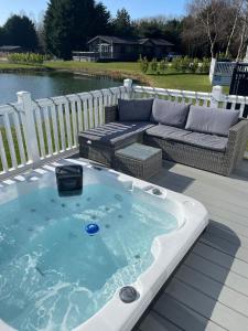 波克灵顿Lakeside Retreat Lodge With Hot Tub的沙发旁甲板上的热水浴池