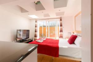 伦敦Centra Wharf的一间卧室配有一张带红色毯子的床和一台电视。
