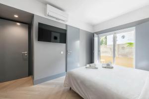 卡斯卡伊斯Jardim Suites by Olala Homes的卧室配有白色的床和平面电视。