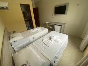 CastanhalGRAN PARADA HOTEL的客房设有3张带白色床单的床和电视。