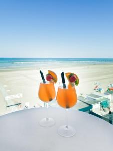 里米尼Riviera Mare Beach Life Hotel的坐在海滩桌子上的两杯鸡尾酒