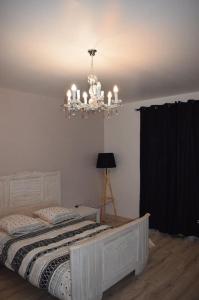 ÉtauliersLe gîte de la palmeraie的卧室配有白色的床和吊灯。