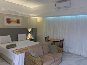马瑙斯Flat Tropical的一间卧室配有一张床、一张沙发和一张桌子