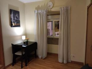 里斯本Apartamento acolhedor no coração de Lisboa的客房设有书桌和带窗帘的窗户。