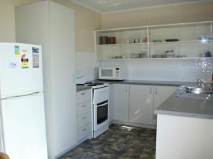黄金海岸White Dolphin Unit 5的厨房配有白色橱柜和白色冰箱。