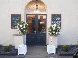 瓦伊河畔罗斯Castle Lodge Wilton的一间商店前方有蓝色的门和鲜花