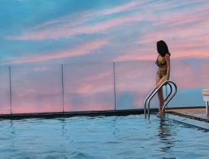 岘港Alani Hotel & Spa的站在游泳池扶手上的比基尼女人