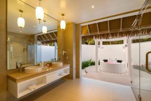 北马累环礁Bandos Maldives的浴室配有2个盥洗盆、浴缸和淋浴。