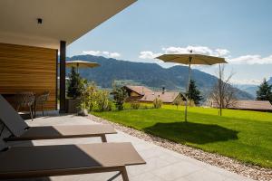 蒂鲁罗Pataunerhof Tilia Lodge的享有草坪景致的带遮阳伞的天井。