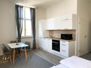 美茵河畔哈瑙Best Boarding House的小厨房配有白色橱柜和桌椅