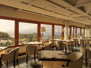 雷焦卡拉布里亚Grand Hotel Excelsior的餐厅设有桌椅和大窗户。