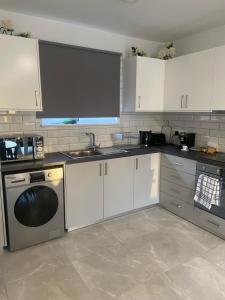 帕福斯Player Sea View apartment的厨房配有白色橱柜、水槽和洗碗机。