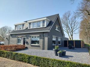 VierlingsbeekB&B Vierlingsbeek, Appartement Onder één dak en tuin-chalet的车道上带灰色屋顶的房子