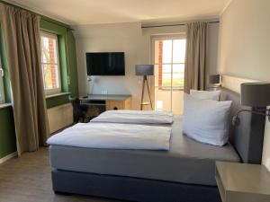 米德尔哈根Hotel & Gasthof Zur Linde的一间卧室配有一张床、一张书桌和一台电视