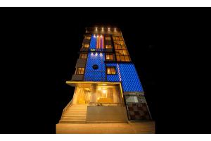班加罗尔FabHotel The Leela Park的一座高大的建筑,晚上有蓝色的灯光