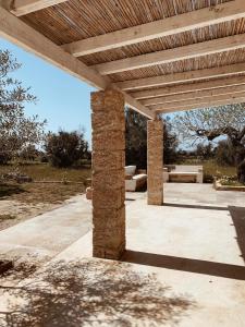 拉卡莱Trullo Contrada Specchi的一个带木制凉亭的石头庭院