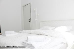 布加勒斯特Black & White - News Apartment的白色的床,配有白色的床单和毛巾