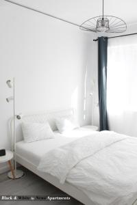 布加勒斯特Black & White - News Apartment的卧室配有白色的床和窗户。
