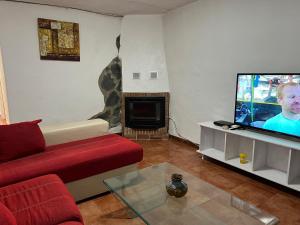 BenalauríaCasa Rural Pimentel的客厅配有红色沙发和平面电视