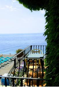 勒托阳尼Hotel San Pietro的海滩上带桌椅的阳台
