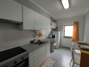 蓬塔德尔加达City Apartament的厨房配有白色橱柜和水槽