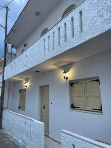PalaiólimnosPhiloxenia traditional house的白色的建筑,设有两扇门和阳台