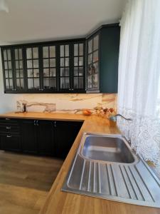 瓦古夫Milusi Domek的厨房配有水槽、黑色橱柜和窗户。