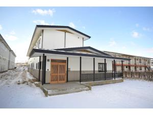 钏路Guest House Tou - Vacation STAY 26333v的雪中带木门的白色建筑