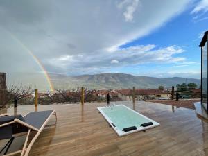 埃尔托尔诺Glamping El Regajo Valle del Jerte的甲板上的游泳池,背面有彩虹