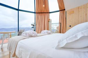 埃尔托尔诺Glamping El Regajo Valle del Jerte的卧室配有白色的床和大窗户