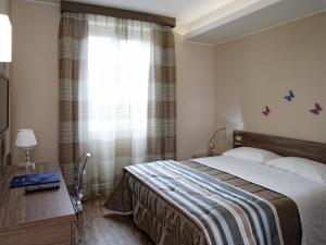 阿西西波尔塔努欧瓦酒店的一间卧室配有一张床、一张书桌和一个窗户。