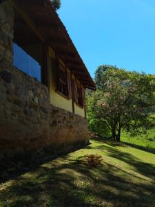 坎波斯杜若尔当Chalé na Serra da Mantiqueira的一座石头建筑,带有窗户和树