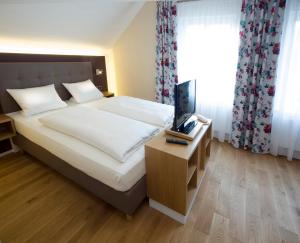 黑里登吉尼博尔利姆巴赫酒店的一间卧室配有一张床和一张桌子及一台电视