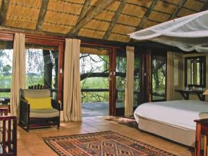 KongolaLianshulu Lodge的一间卧室配有一张床、一把椅子和窗户。