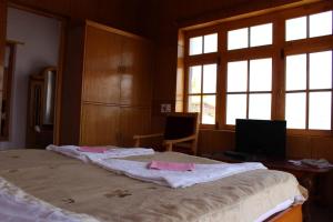 列城Hotel Skittsal Leh的一间卧室配有一张大床、书桌和窗户