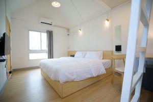 佛统Barn Sampran Resort บ้านสามพรานรีสอร์ท的一间卧室配有一张床、一张书桌和一台电视