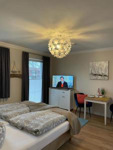 奥斯特巴特宁哈根Ostseestrand-Apartments的一间卧室配有一张床、一台电视和吊灯。