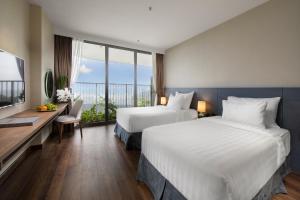 吉婆岛Flamingo Premium Cat Ba Beach Resort的酒店客房设有两张床、一张书桌和窗户。