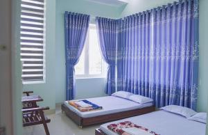 An Bình (1)MINH THU MOTEL的一间卧室设有两张床,窗户配有蓝色窗帘
