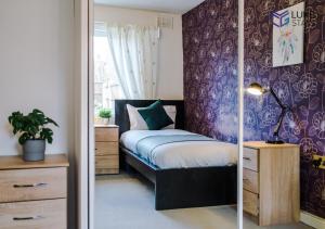 SeftonLuke Stays - John Hunter Way的一间卧室配有一张床和紫色的墙壁