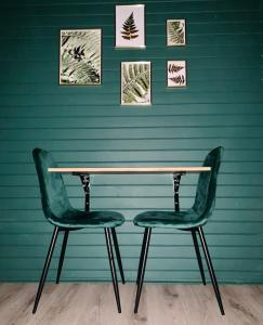 WielbarkKarczma Leśniczanka的一张桌子和两把椅子靠着绿色的墙壁