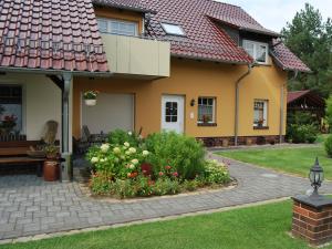 吕本Pension + Apartments Tor zum Spreewald的黄色的房子,前面有一个花园
