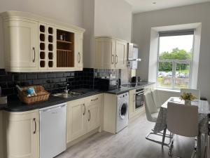 阿马Dympna's City Centre apartment, Armagh的厨房配有白色橱柜、水槽和洗碗机。