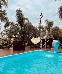 普腊亚罗萨Pousada Altos do Rei的一个带椅子和棕榈树的蓝色游泳池