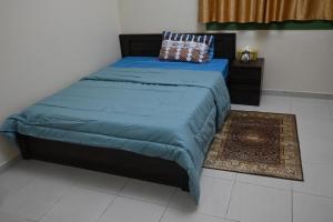 沙迦Entire Studio Flat in Sharjah.的一间卧室配有一张带蓝色毯子和地毯的床。