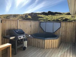 塞尔福斯EYVÍK Cottages - Private HOT TUB!的木制甲板上的热水浴池和烧烤架