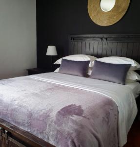 利隆圭Bamboo Boutique Hotel的一间卧室配有一张带紫色枕头的大床