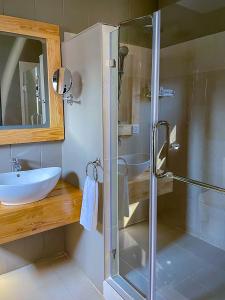 利隆圭Bamboo Boutique Hotel的一间带玻璃淋浴和水槽的浴室